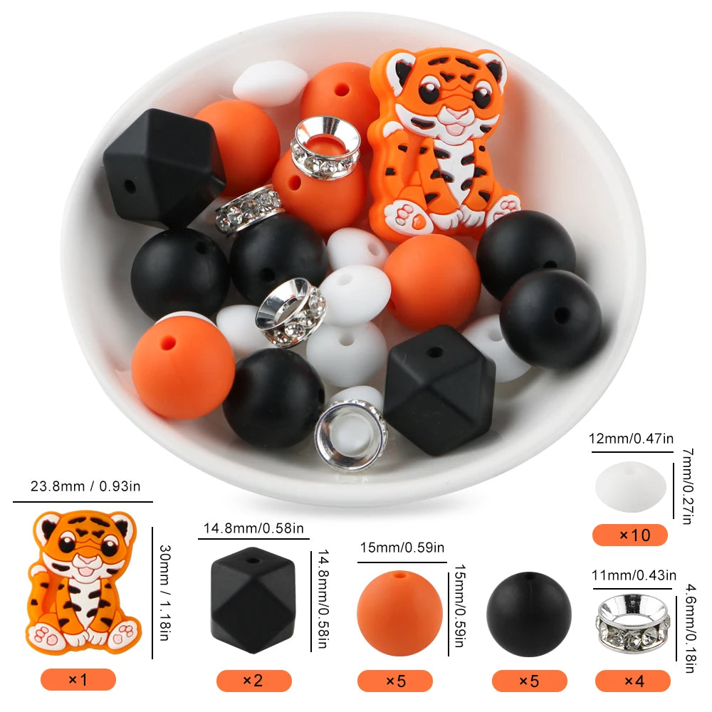A white bowl filled with various orange and black silicone beads shaped like a tiger, including round, flat, and ring-shaped 