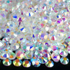A close-up view of a pile of clear and iridescent sparkling crystal flatback rhinestones for nail art and crafts.