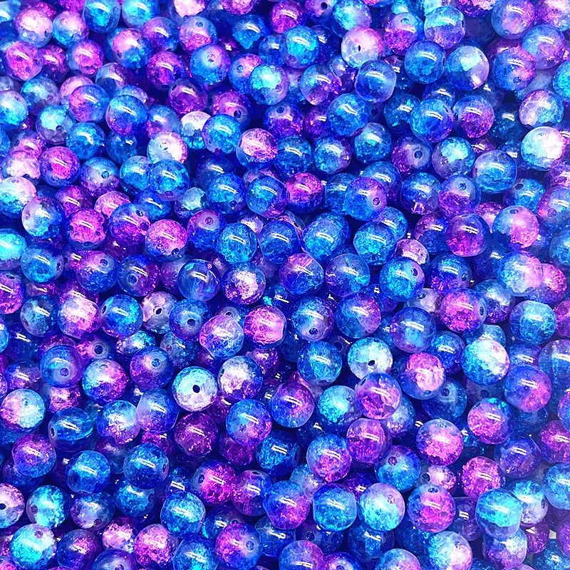 A close-up view of many round glass crackle beads in various shades of blue and purple.