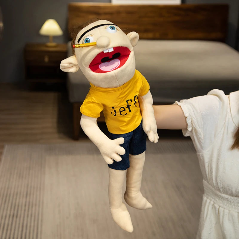 A realistic plush hand puppet resembling a man with blonde hair and a yellow shirt is being held by a person.
