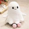 A white ghost plush toy with black eyes and pink feet sitting on a light-colored surface.