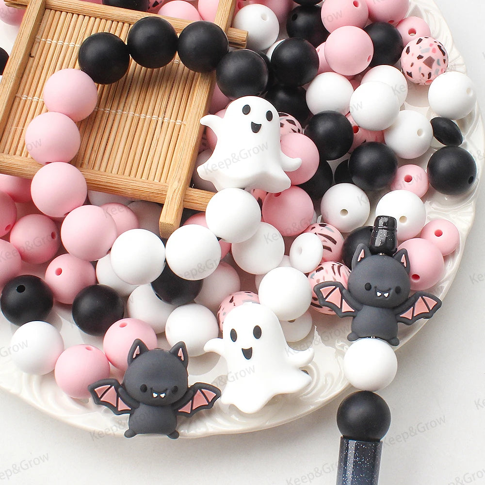 A collection of pink and black silicone crafting beads arranged on a white plate with a wooden grid background.