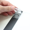 A hand is placing a clear plastic protector cover onto a black light pad switch.