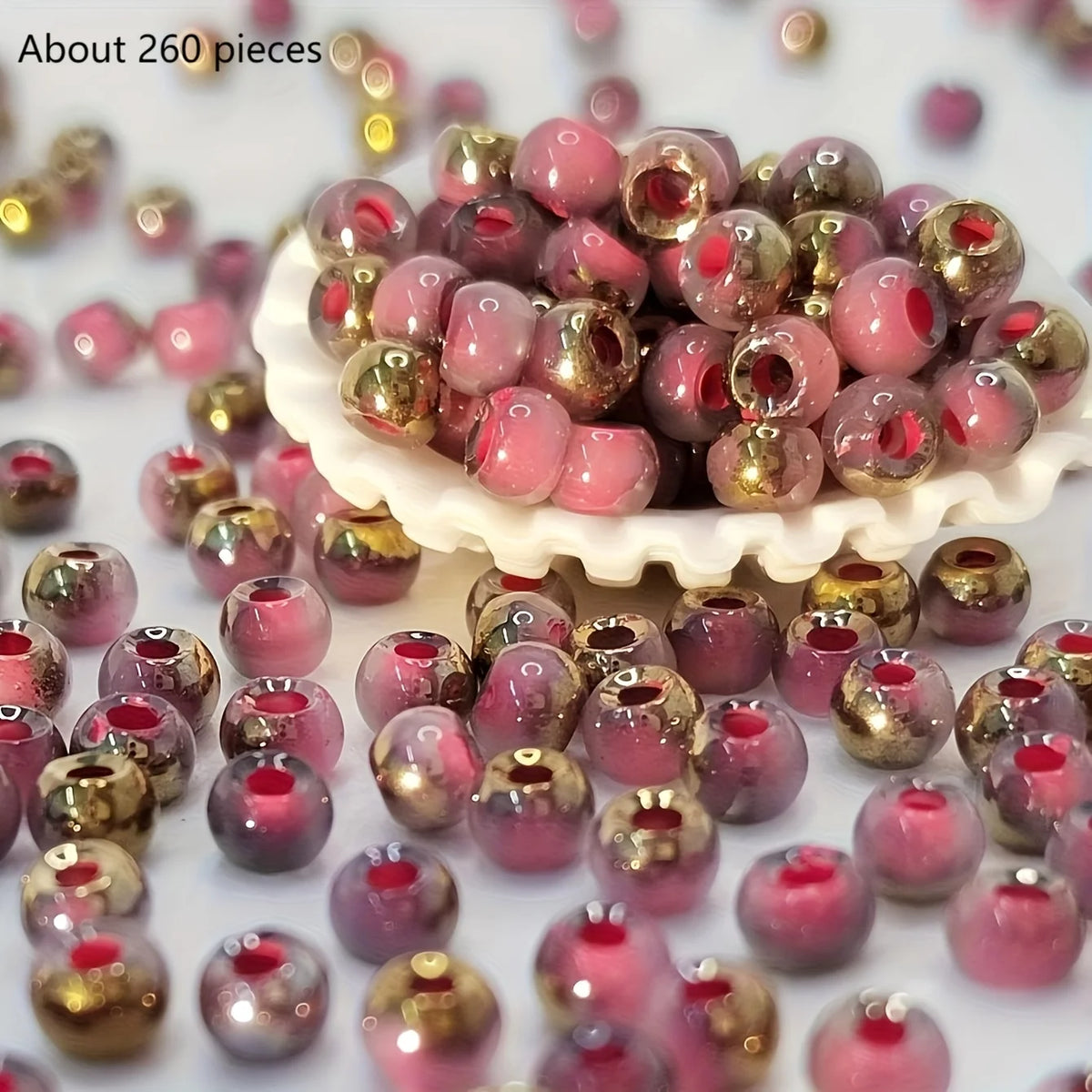 A pile of vibrant round beads in pink and gold colors scattered on a white surface.
