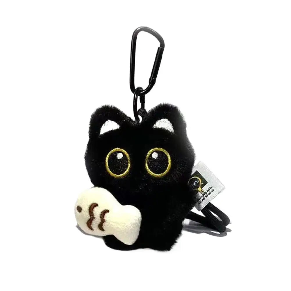 A black plush cat keychain with gold eyes and a white paw detail.