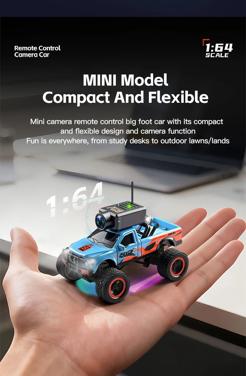 A hand holds a blue and orange 1:64 scale RC monster truck with an attached camera.