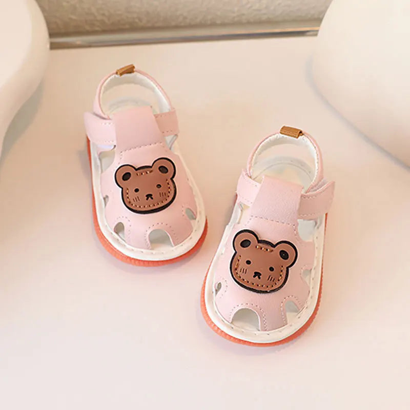 Une paire de sandales d'été antidérapantes en bear rose et bruyantes pour bébés, posées sur une surface blanche.