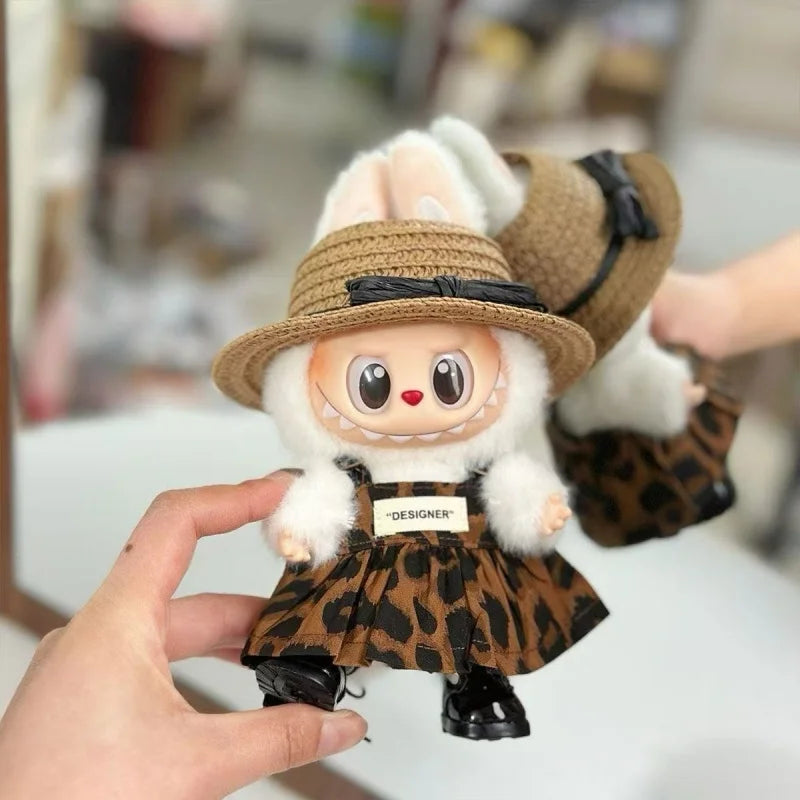 A handmade plush doll dressed in a leopard print outfit and hat being held by a hand.