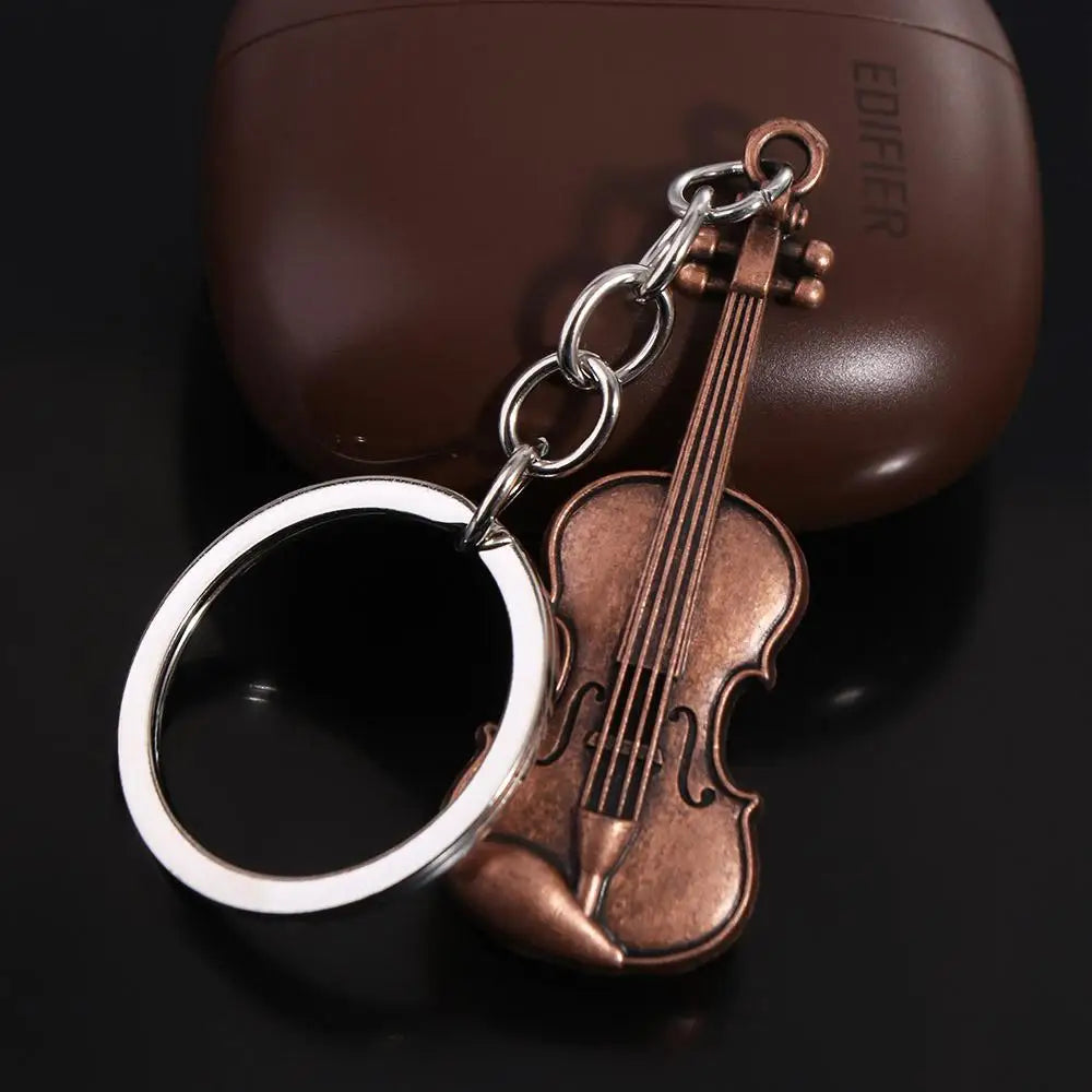 A vintage violin-shaped keychain with a silver ring attached to a brown leather case.