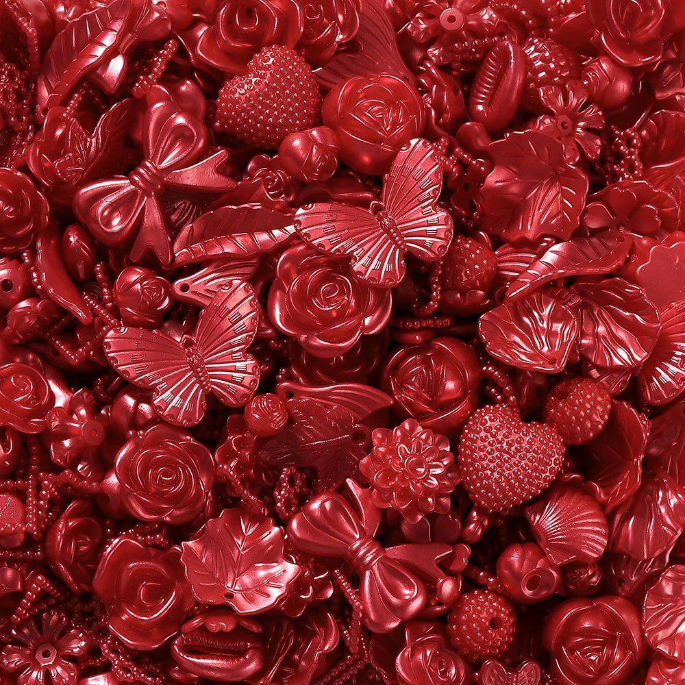 A close-up of red and pink acrylic butterfly shell beads used for DIY jewelry making.