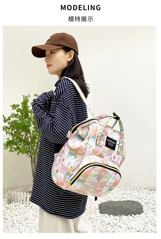 A woman models a pink cartoon print waterproof diaper bag for travel and stroller.