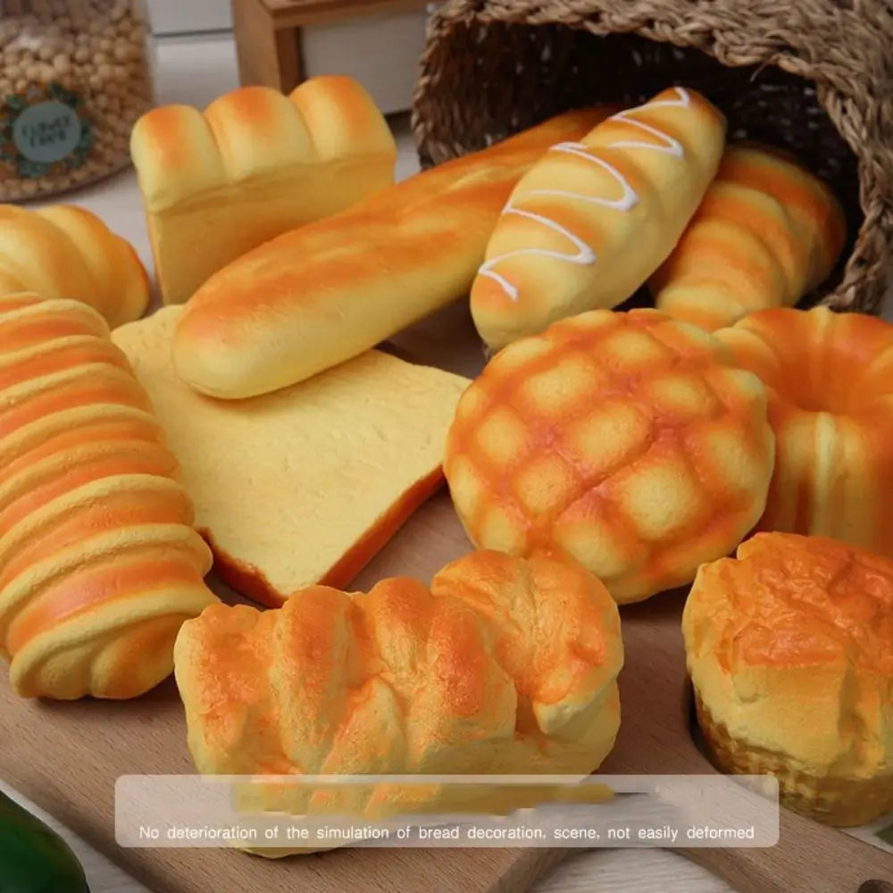 A variety of realistic bread-shaped toys and food items are displayed on a wooden surface.