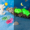 Two glow in the dark mini turtle figurines, one green and one pink, displayed in daytime and nighttime settings.
