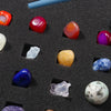 A collection of polished natural crystals and minerals in various colors including red, orange, purple, blue, and white on a 