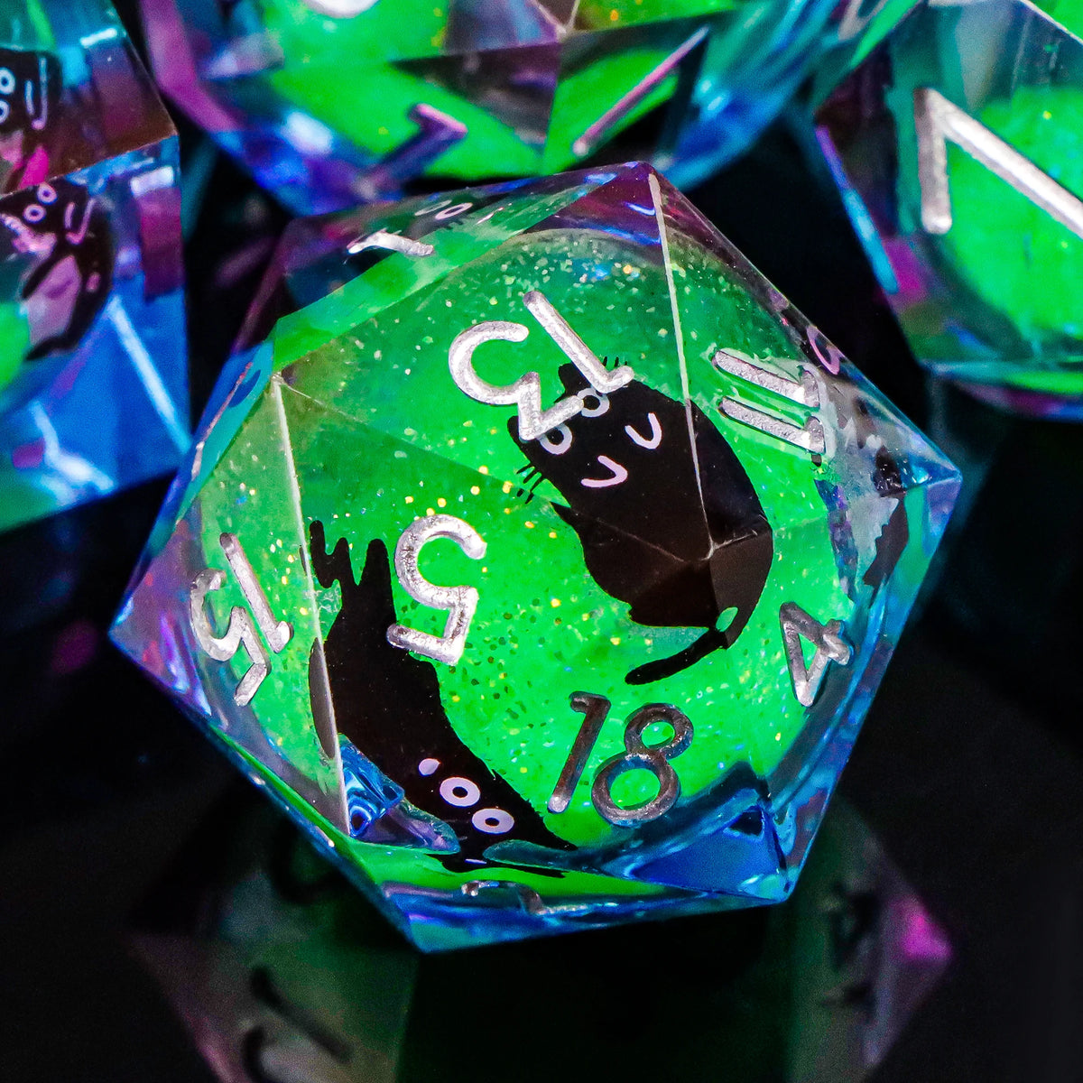 A close-up of a translucent green resin die showing a black cat silhouette and various numbers.