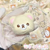A hand holds a squishy stress relief toy shaped like a cute pink bear with white accents.
