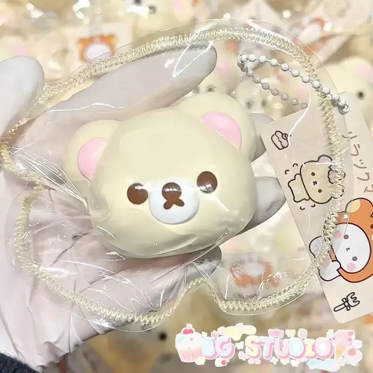 A hand holds a squishy stress relief toy shaped like a cute pink bear with white accents.