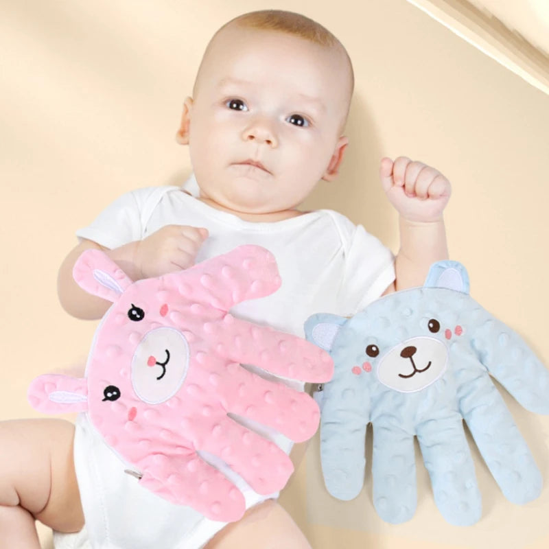 Un bébé tient un massageur de main rose et un massageur de main bleu.