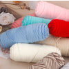 A collection of three skeins of soft cotton blend yarn in various pastel and bright colors like pink, blue, red, and cream.