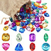 A collection of colorful acrylic gemstones including rubies, sapphires, emeralds, and citrine scattered on a burlap fabric.