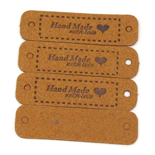 A set of three brown leather-style handmade tags with a heart design for crafts and sewing.