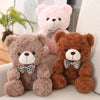 Two teddy bear plush pillows, one pink and one brown, with bows.