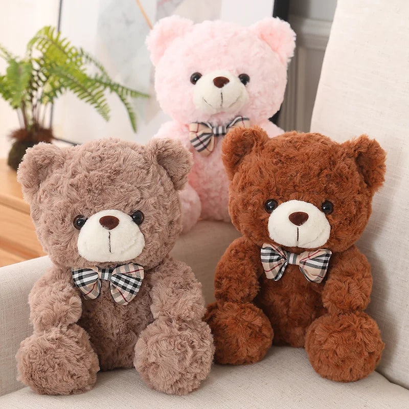 Two teddy bear plush pillows, one pink and one brown, with bows.