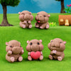 Three small, round, pinkish-brown resin hippo figurines sitting on green grass.