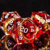 A close-up of a set of red resin dice with golden elven numbers, angled against a dark background.