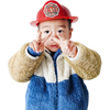 A young child wearing a red firefighter helmet and a blue and white fuzzy jacket making a peace sign.