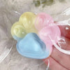 A hand holds a translucent squishy toy shaped like a cat paw with multiple pastel colored sections.