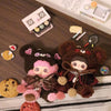 A plush charm of a brown bear with pink hair and clothing sits next to various small candies and accessories.