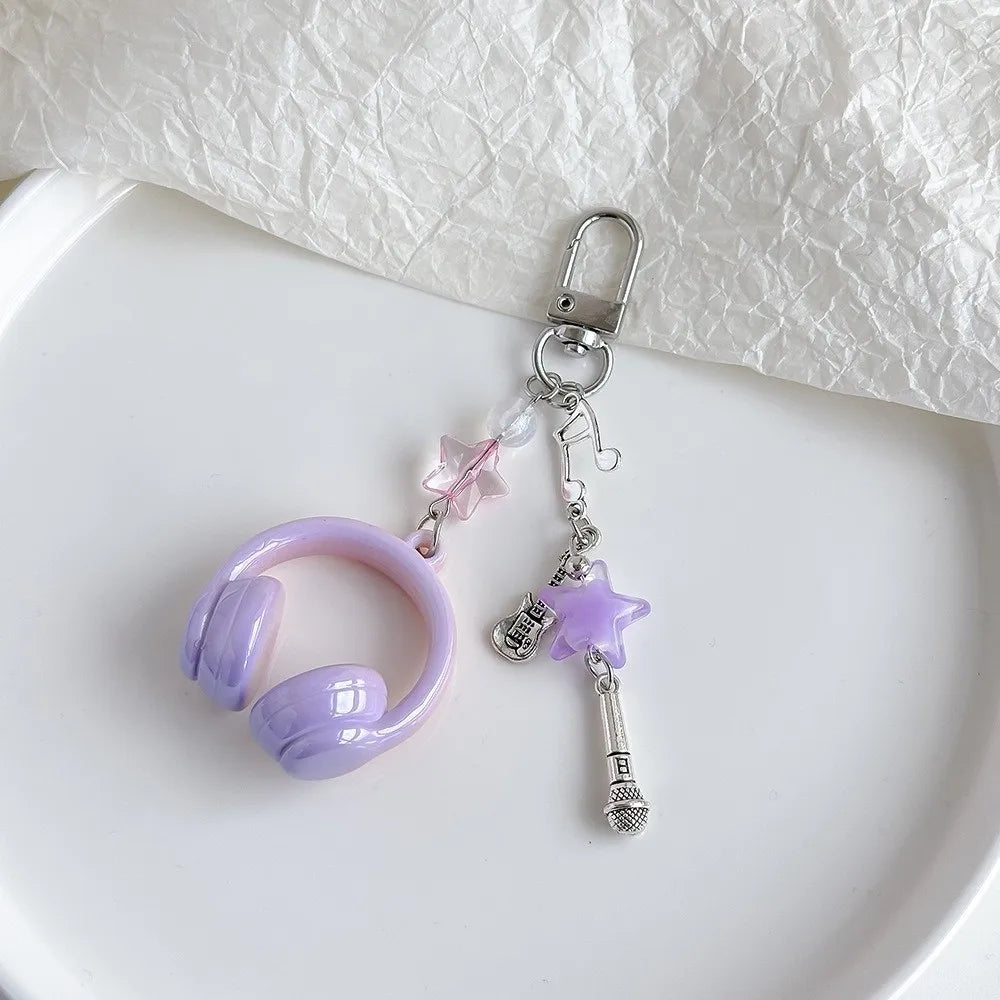 A purple beaded wing cross phone lanyard keychain attached to a silver clasp, resting on a white surface.
