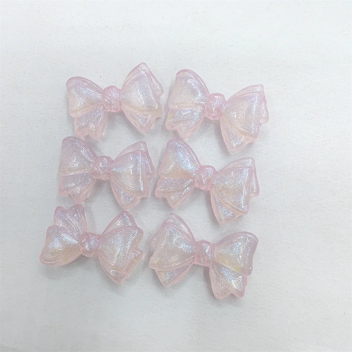 A collection of pink, iridescent mermaid-themed bowknot beads for jewelry making.