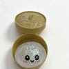 A light green silicone stress ball shaped like a dumpling with a smiling face.