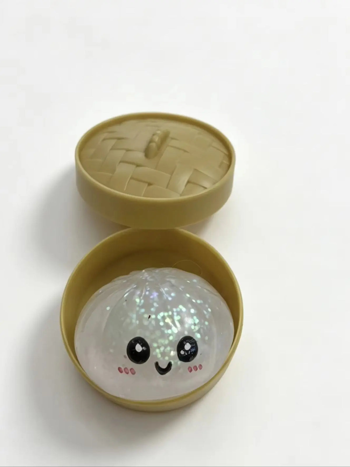 A light green silicone stress ball shaped like a dumpling with a smiling face.