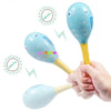 A hand holds a light blue wooden sand hammer percussion instrument for kids against a white background.