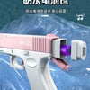 A pink electric automatic water gun is shown in a close-up, resting on a blue textured surface.