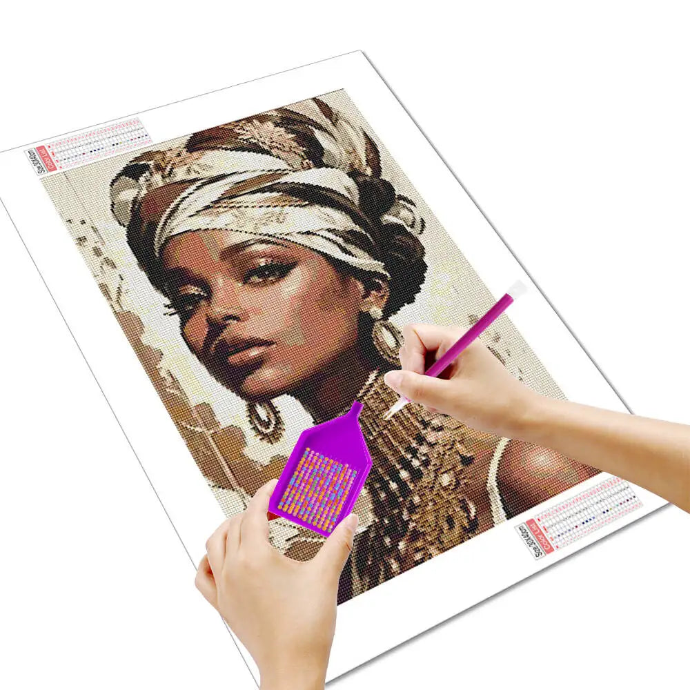 A hand is painting a portrait of an African woman with a diamond painting kit on a canvas.