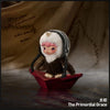 A plush doll pendant featuring a character with pink hair and white fur, resting on a red dish.