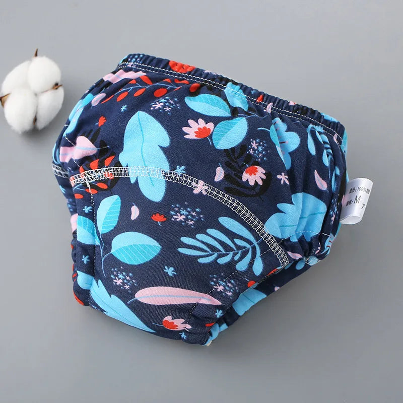 Paquete de calzoncillos de entrenamiento lavables a juego con estampado azul para bebés, con una bola de algodón blanca cerca