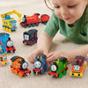 A young child is interacting with various Thomas & Friends diecast train toys on a light-colored carpet.