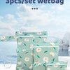 Three light green fabric wet bags with white daisy patterns are displayed on a white surface.