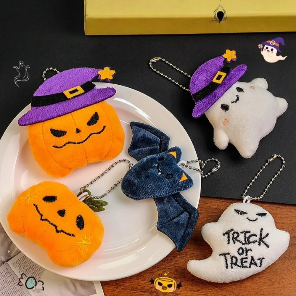 A set of Halloween plush keychains featuring a ghost, pumpkin, and bat charm on a white plate.