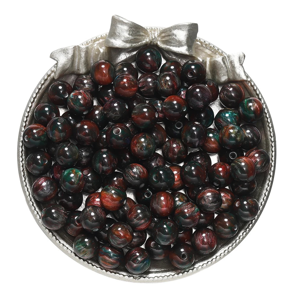 A small silver dish filled with dark reddish-brown and green glitter resin beads for jewelry making
