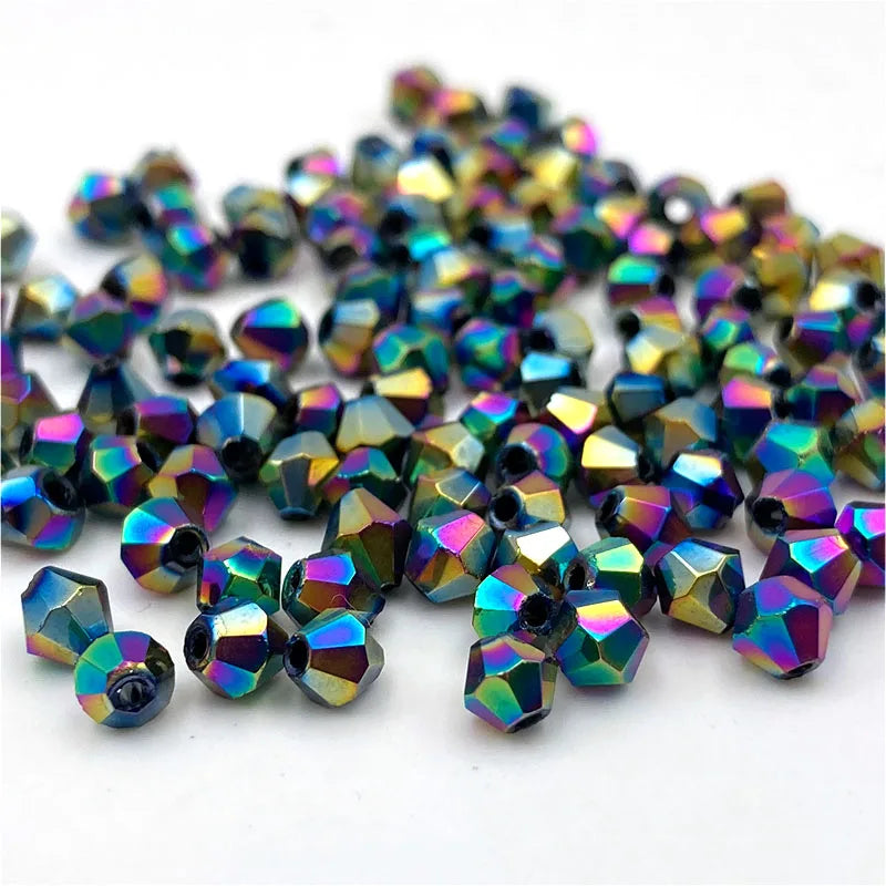 A pile of small, faceted bicone crystal glass beads in iridescent colors for jewelry making.