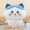 A white and blue Chiikawa plush doll with large eyes sitting on a textured surface.