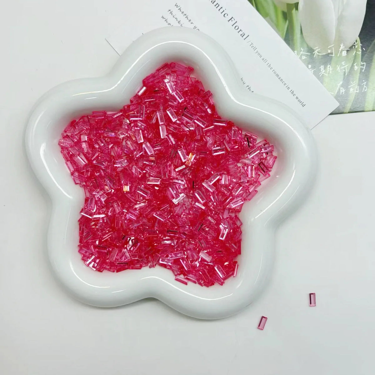 A white flower-shaped mold filled with bright pink and red acrylic ice strips for nail art and DIY crafts.