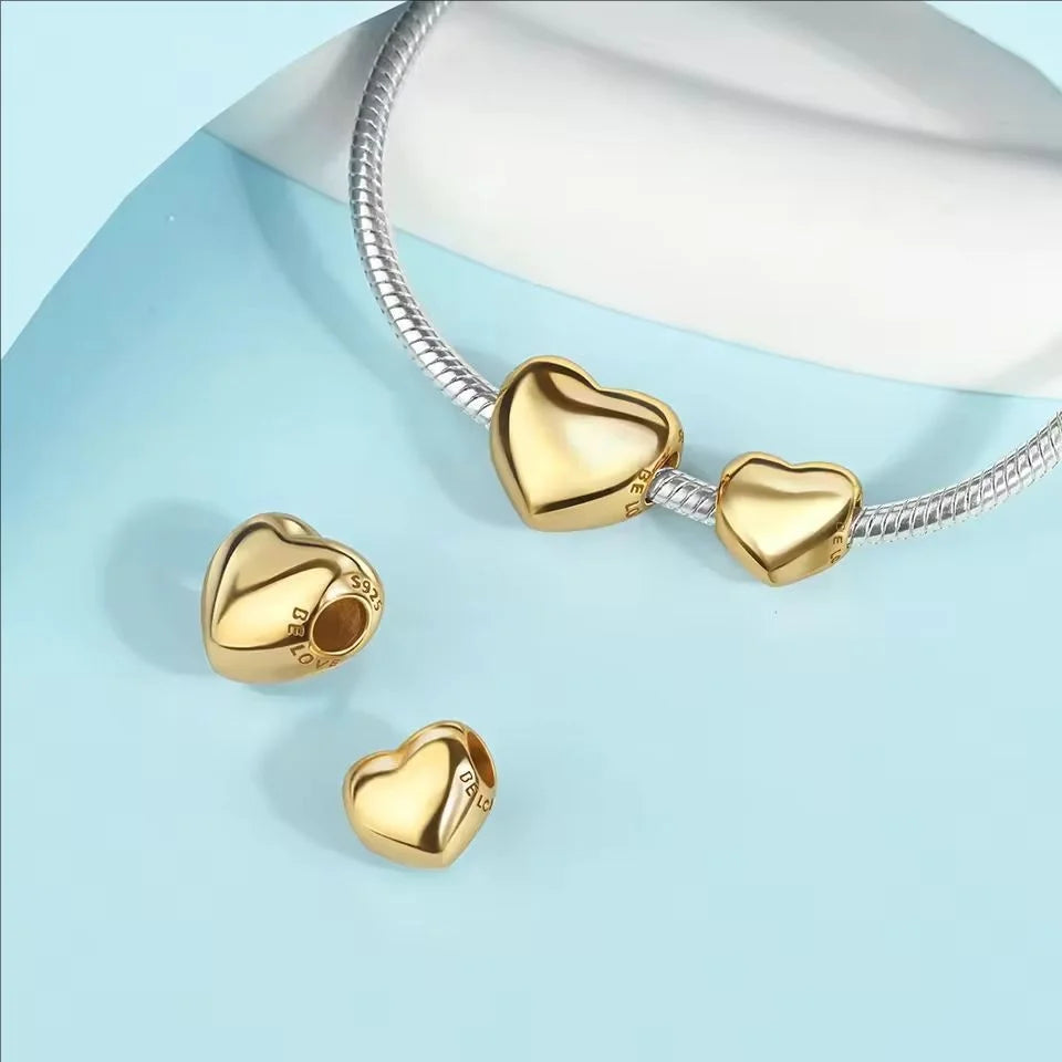 Gold heart charms attached to a silver chain displayed on a light blue background.
