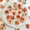 A white plate decorated with floral hot stamp stickers in shades of orange and red.